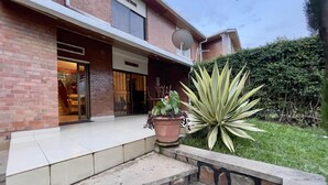Une maison moderne avec une façade en briques, une grande antenne parabolique et un jardin bien entretenu, agrémenté d’un agave bien visible.