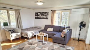 Una sala de estar con sofá, sillón, mesa de centro y una alfombra estampada.