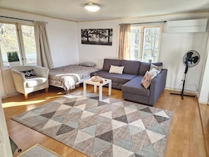 Una sala de estar con sofá, sillón, mesa de centro y una alfombra estampada.
