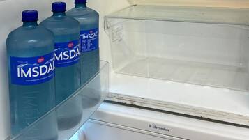 A refrigerator with three IMSDAL water bottles on the door shelf.