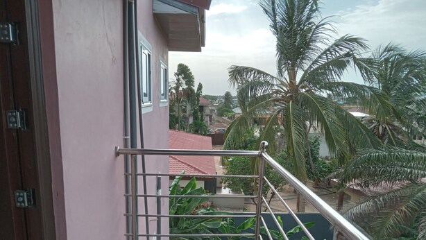 Ein Balkon mit Metallgeländern, der auf ein Wohngebiet mit Häusern und Palmen blickt.