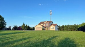 A two-story house with a garage, surrounded by a large grassy yard and trees. - Spacious 4-bedroom home in private nature (Moore)