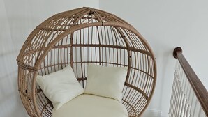 A round, woven chair with a cushion, placed on a woven mat. - Spacious 4-bedroom home in private nature (Moore)