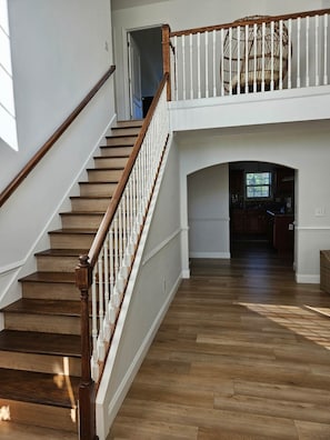 Staircase leads to an upper landing with a decorative chair, surrounded by open spaces and natural materials.