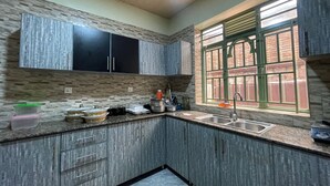 Una cocina con salpicadero de piedra, armarios oscuros, una ventana con marcos verdes y un lavamanos.