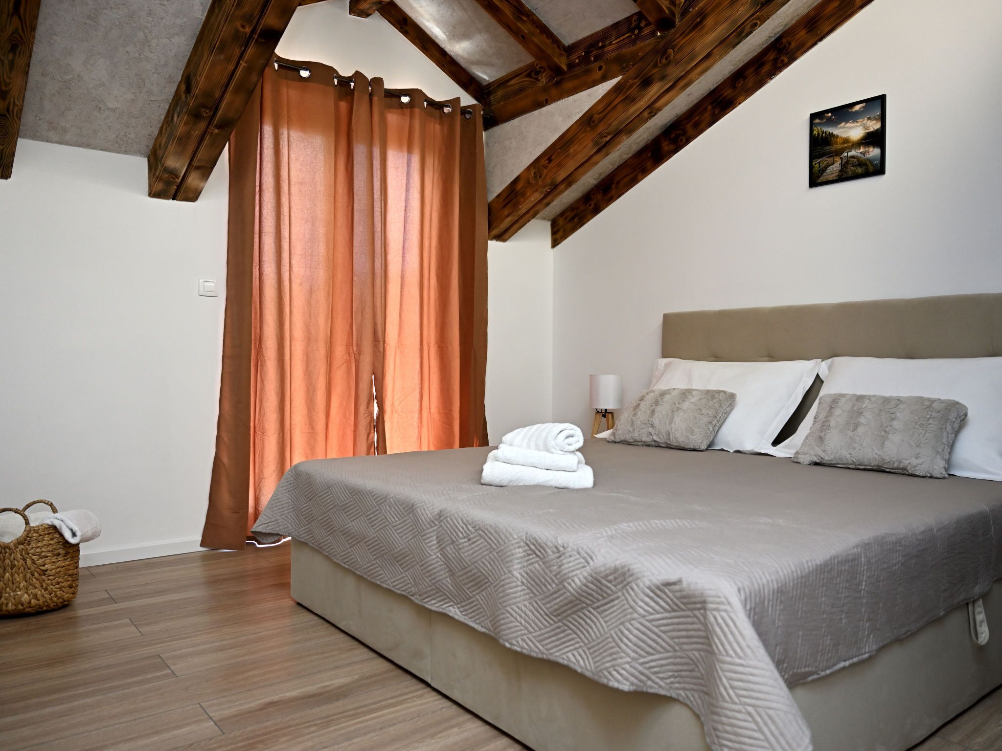 Une chambre à coucher avec un lit, une tête de lit, une table de chevet, une lampe et un tableau au mur.