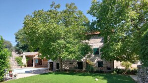 Un bâtiment en pierre avec une cour verdoyante et un arbre devant.