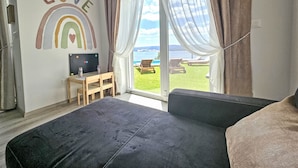 Een slaapkamer met een groot bed, een bureau met een computer en uitzicht op een zwembad en terras.