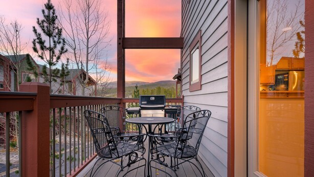 Una terraza con mesa y sillas, con vistas a un paisaje pintoresco con montañas y árboles.