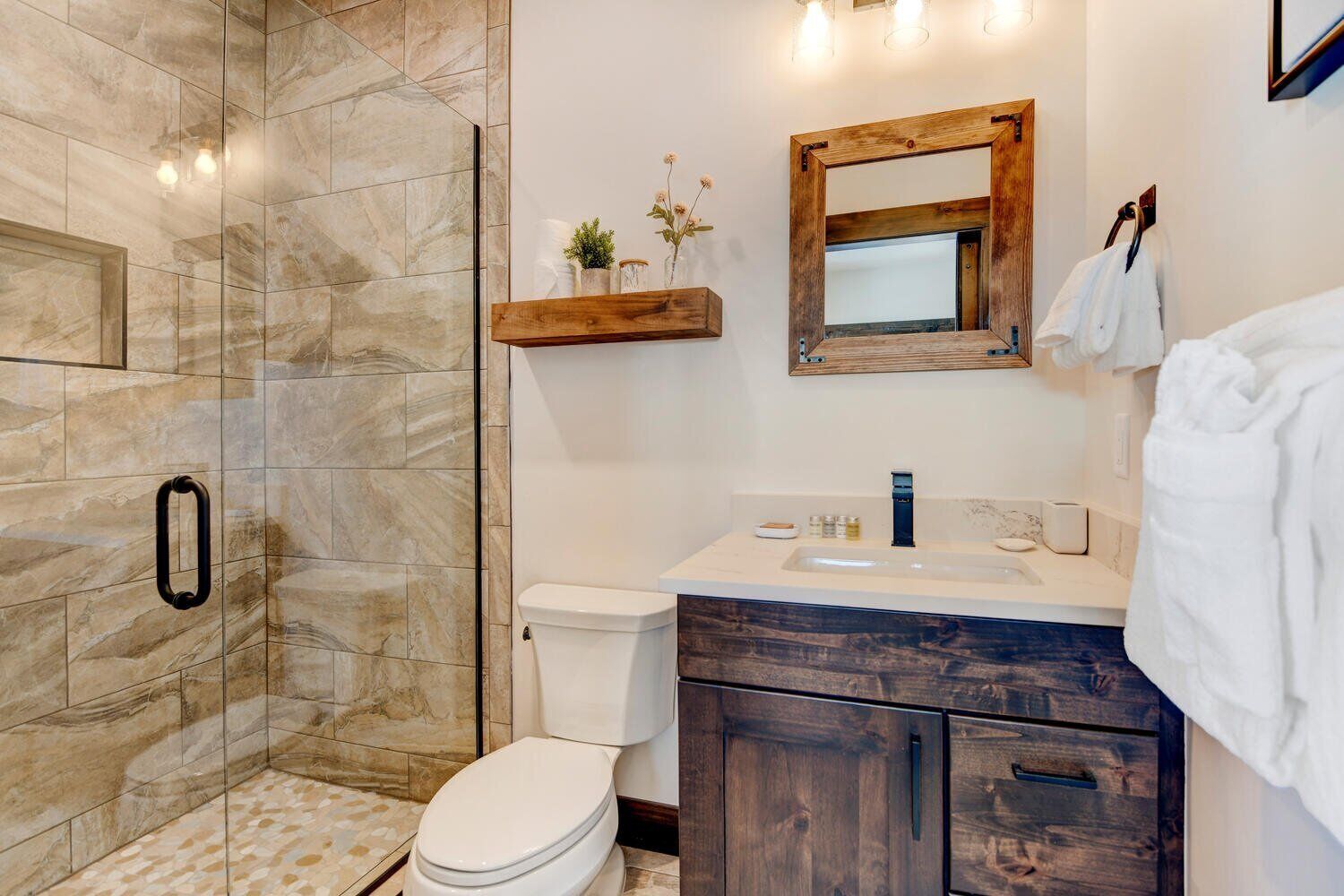 Une salle de bain équipée d’une douche, de toilettes, d’un lavabo et d’un miroir.