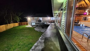 Una casa con un patio de piedra, piscina y terraza de madera.