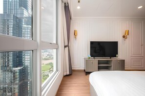 Een moderne hotelkamer met een groot raam, een flatscreen televisie, een bed en een klein bureau.