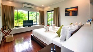 A hotel room with a large bed, a TV, a window with curtains, a painting, and a wooden chair.