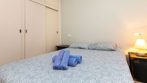Ein Schlafzimmer mit Bett, Nachttisch, Lampe und Kleiderschrank.