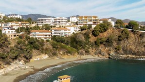 Uma área residencial costeira com edifícios altos, uma praia e terreno rochoso.