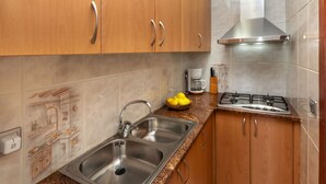 Una cocina con gabinetes de madera, fregaderos de acero inoxidable, una estufa a gas y una cafetera.