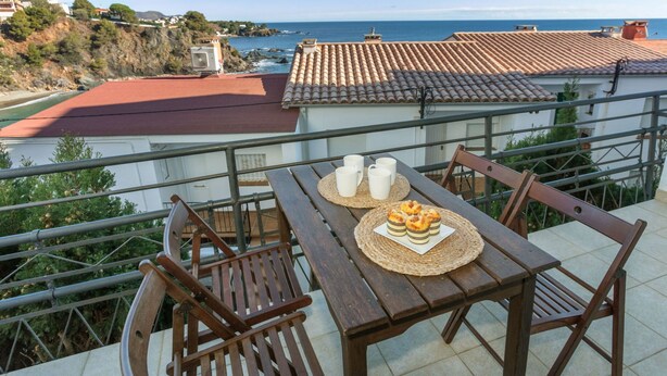 Un balcón con una mesa dispuesta para dos, con vista al mar.