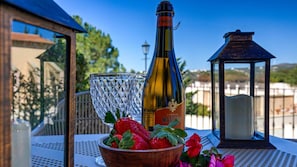 A bottle of Cantina Maschio wine, a glass, and a bowl of strawberries on an outdoor table.