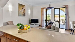 A modern living room with a large island counter, a flat-screen TV, a sofa, and a dining area.