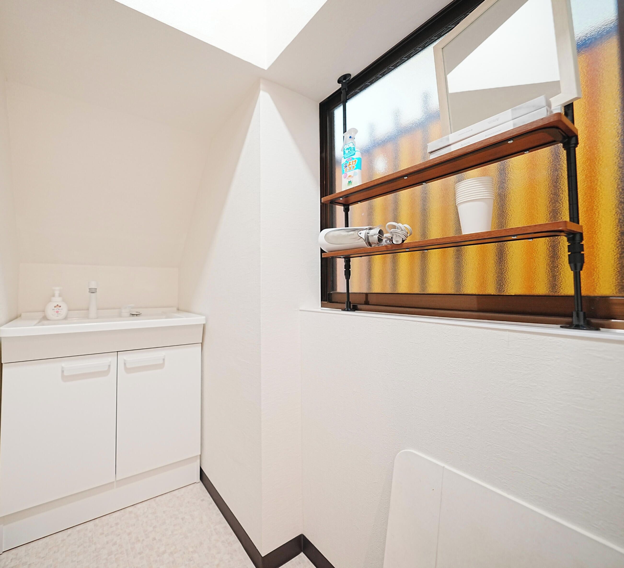 A small, bright bathroom with a skylight, a white sink, and a shelf with toiletries.