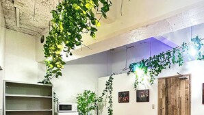 Una sala conferenze con tavolo in legno, sedie nere, una lavagna e piante verdi.