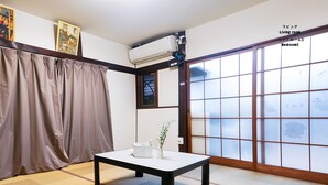 Una stanza tradizionale in stile giapponese, con pavimento in tatami, una porta scorrevole shoji e un tavolo con un vaso di fiori.
