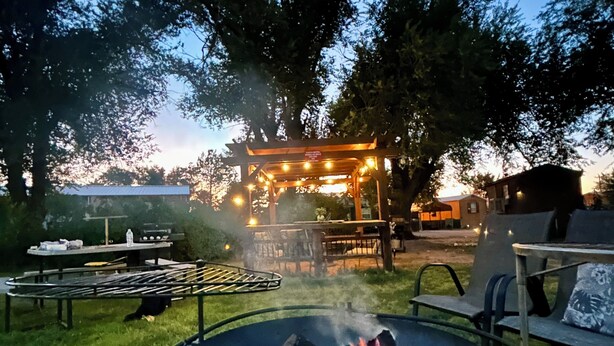A backyard with a fire pit, picnic table, and a covered seating area. - The Lodge at Ute Lake (Logan)