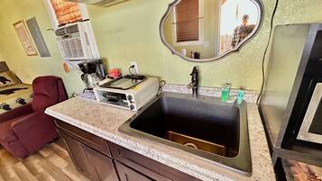 A kitchen with a built-in oven, a sink, a mirror, and a red chair.