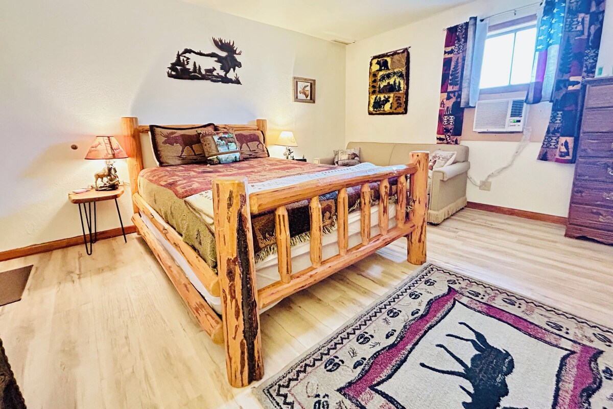 Een gezellig slaapkamer met een houten bed, een klein nachtkastje, een lamp en decoratieve moos kunst aan de muur.