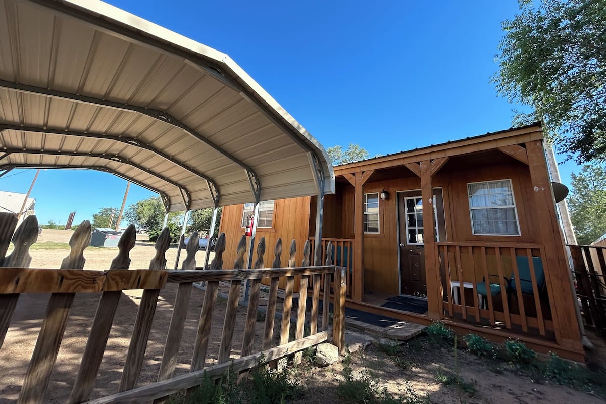 A wooden cabin with a porch and a covered area.