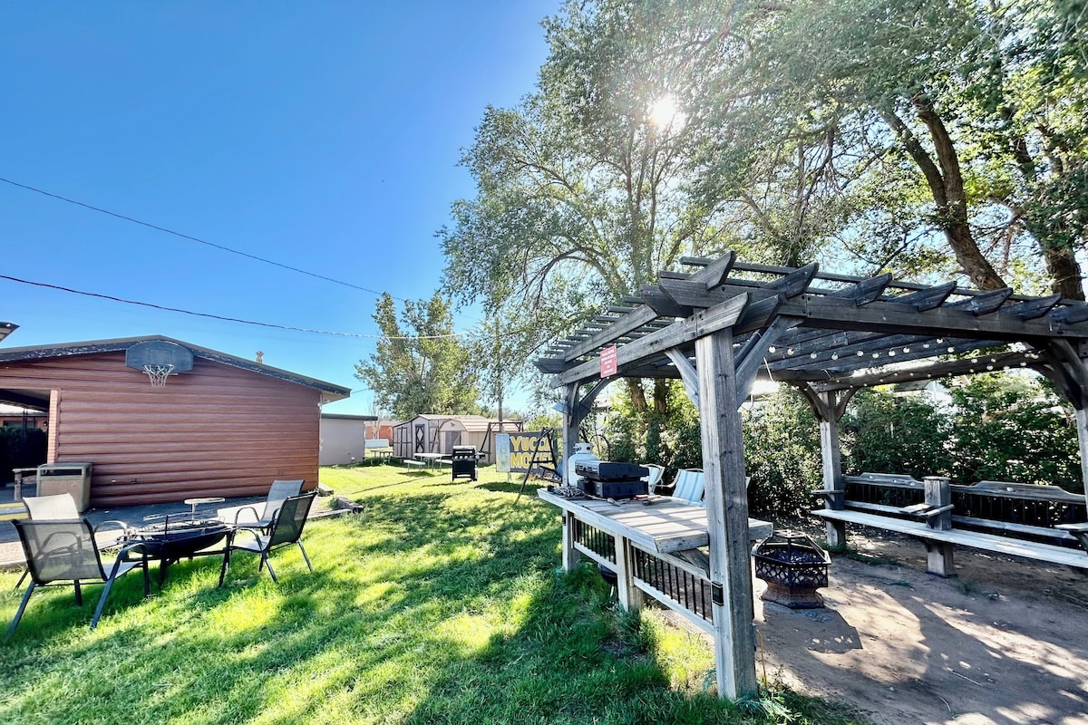 A backyard with a wooden pergola, a barbecue grill, and a small shed.