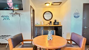 A cozy room with a round wooden table, two chairs, a television mounted on the wall, a mirror, and a rug. - The Lodge at Ute Lake (Logan)