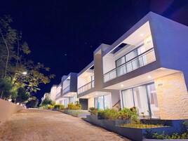 Un hôtel moderne doté de nombreux balcons, d’une allée pavée et d’un aménagement paysager bien entretenu.