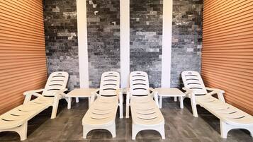 Een wellnessruimte met witte lounge fauteuils en een achtergrond van een stenen muur.