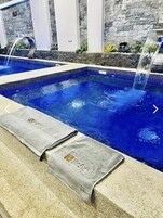 Une piscine avec un mur en pierre en arrière-plan et un élément décoratif aquatique.