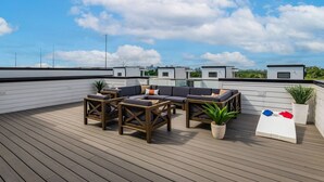 A rooftop deck with a wooden floor, a sectional sofa, and a small table. - Howdy Honey! 8 Beds ~ Hot Tub with Double Deck Rooftop & Amazing City Views  ~ 3 Miles to Broadway! (Nashville)