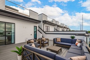 Une terrasse sur le toit dotée d’un espace salon extérieur moderne, comprenant un canapé et des fauteuils, ainsi qu’une plante en pot.