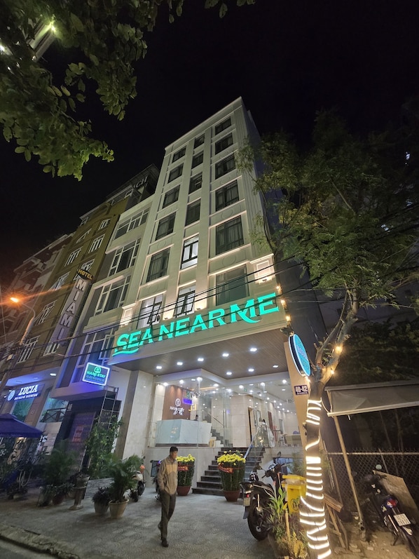 A hotel with a prominent 'SEANARME' sign, multiple floors, and a well-lit entrance.