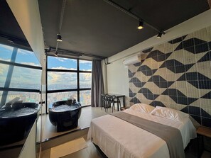 A hotel room with a large bed, a bathtub, a desk, and a view of the city. - Sky Loft São Paulo (São Paulo)