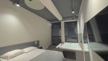 Een moderne hotelkamer met een bed, een badkuip en een groot raam met uitzicht op de stad.