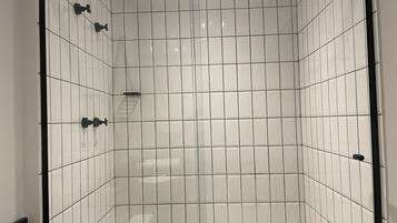 A modern shower with white tiles and black fixtures.