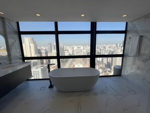 A modern bathroom with a large bathtub, a marble floor, and a city view through large windows. - Sky Loft São Paulo (São Paulo)