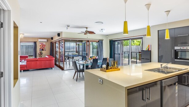 A modern kitchen with a central island, a dining area with a red sofa, and a pool table. - Stylish 2BR House for a Memorable Stay @Stretton (Stretton)