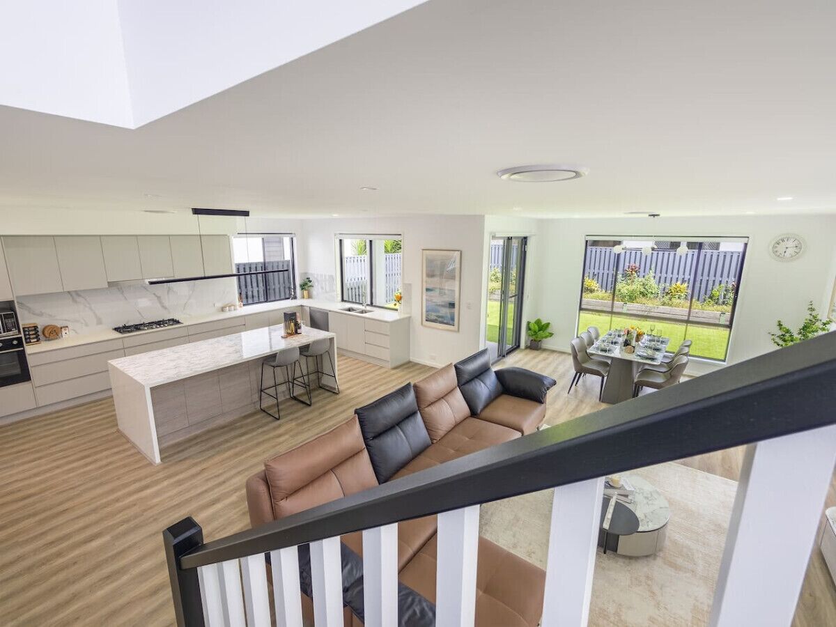 A modern kitchen with a central island, a dining area with a table and chairs, and a living room with a sofa.