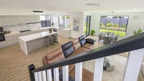 Cozinha moderna com ilha central, área de jantar com mesa e cadeiras, e sala de estar com sofá.
