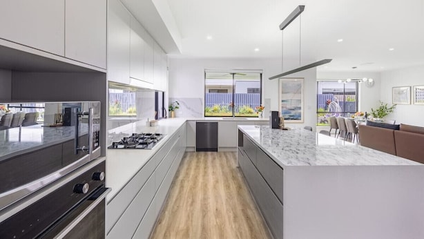 Cozinha moderna com ilha central, eletrodomésticos embutidos e vista para o exterior.