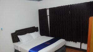 A hotel room with a bed, black curtains, and a wooden floor. - DE HOMESTAY BANJARMASIN (Banjarmasin)