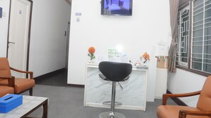 A reception area with a reception desk, a television mounted on the wall, and two chairs. - DE HOMESTAY BANJARMASIN (Banjarmasin)