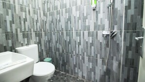 A bathroom with a toilet, a sink, and a shower. - DE HOMESTAY BANJARMASIN (Banjarmasin)