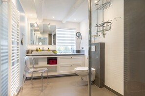 A modern bathroom with a white vanity, a toilet, a shower, and a glass shower enclosure. - Gaat 7 Der Junge Heinrich - Gaat 7 - Wohnen im Historischen Ortskern Keitum (Sylt)